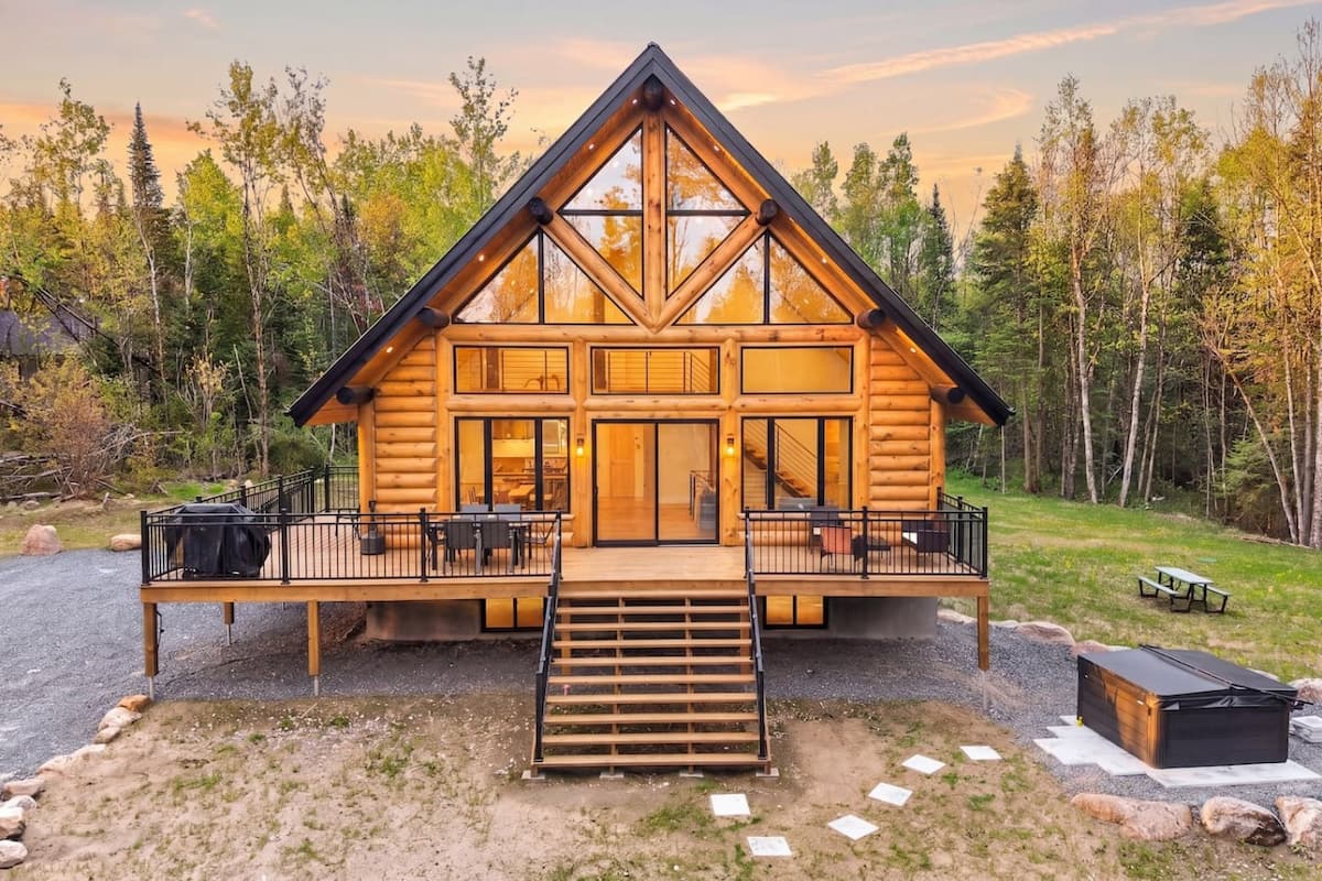 Front exterior of Mosaic Chalet with a wide deck and forest backdrop